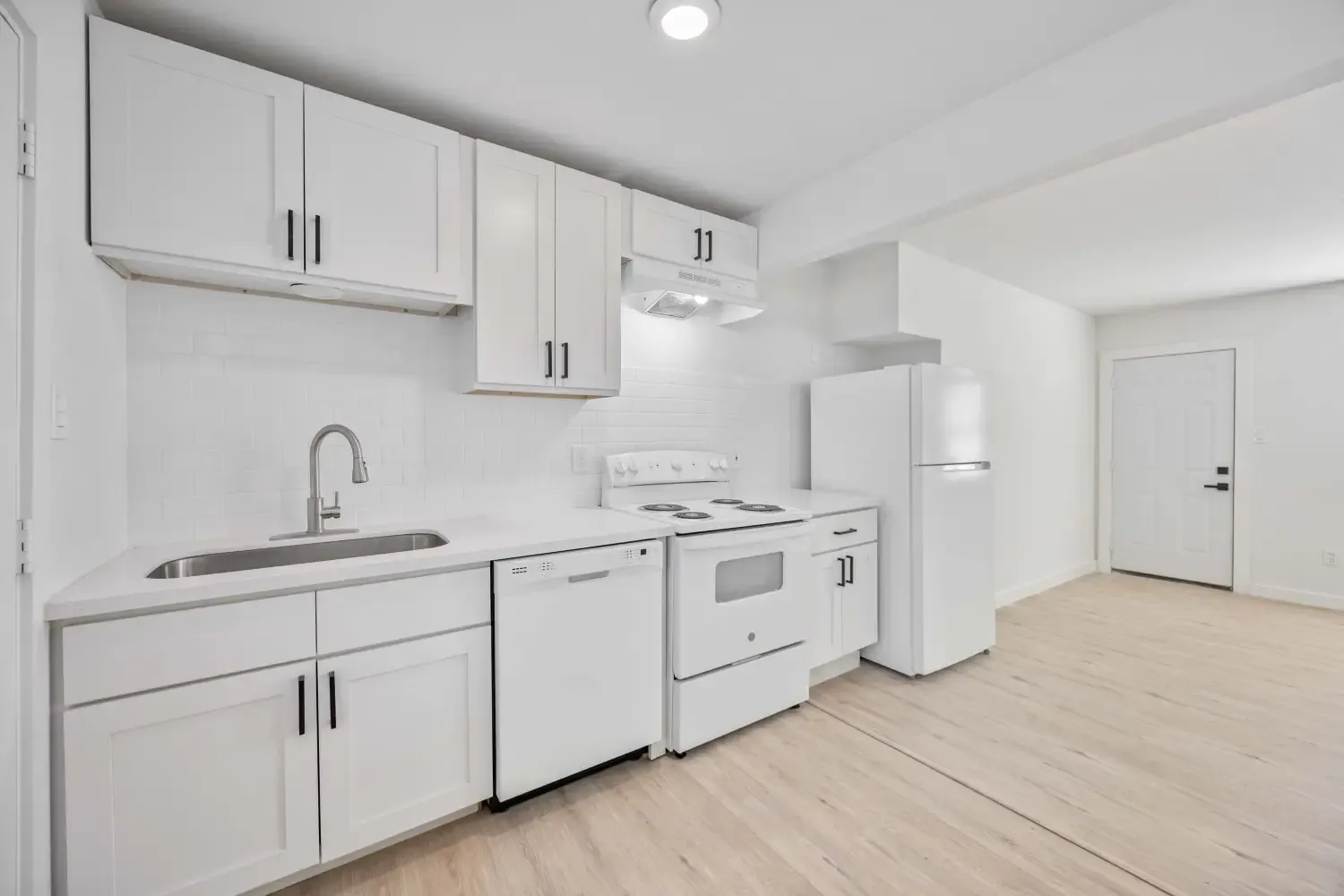 Updated kitchen with white shaker cabinets, stainless sink, and range at Habitat at The Medical Center