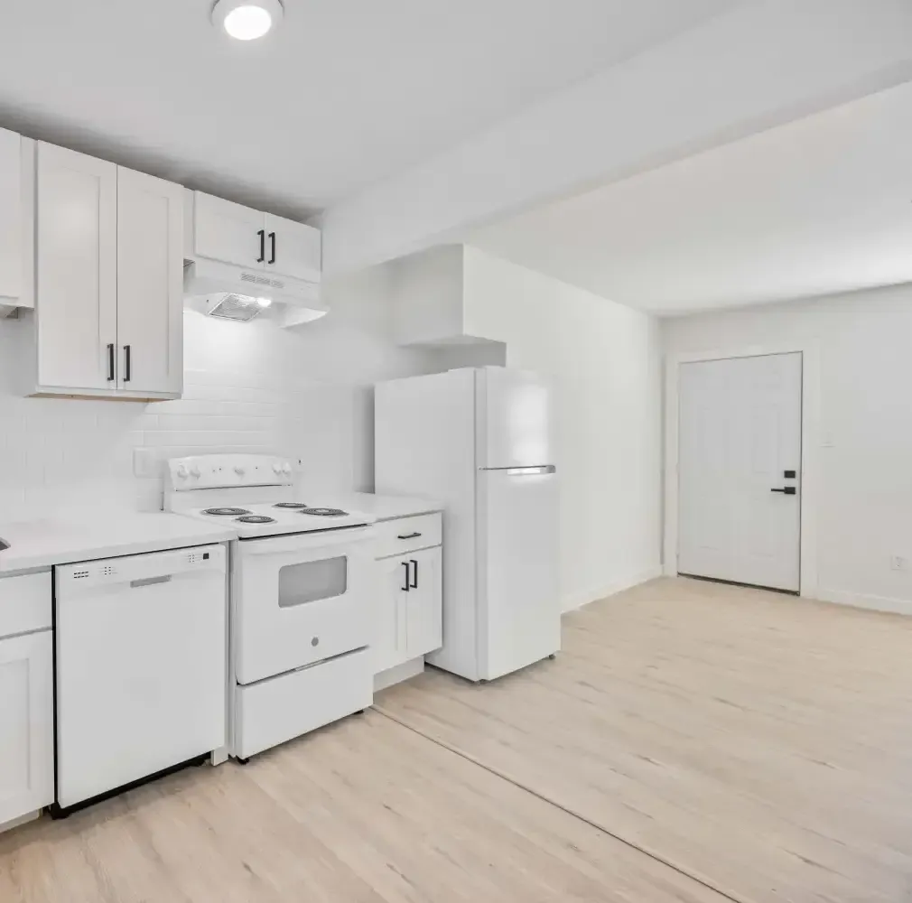 Open kitchen with white cabinets, dishwasher, and range